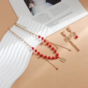 Nahaufnahme von rotem Perlen-Schmuckset mit hohlen Flügel-Anhängern und Quasten