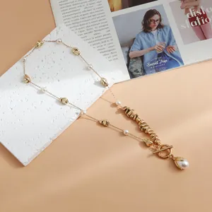 Detail view of a gold alloy necklace with irregular metal beads and pearls.