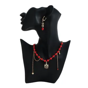 Nahaufnahme von Schmuckset mit roten Perlen und hohlem Flügel-Totem-Anhänger.
