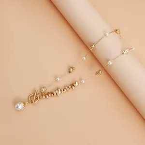 Detailed view of an irregular gold-tone metal bead and pearl necklace with toggle clasp