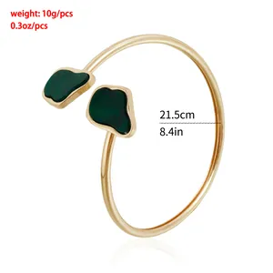 Detail view of retro gold open bangle with irregular green stones and dimensions