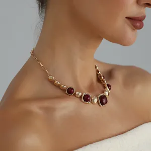 Close-up of vintage geometric gold-tone necklace with burgundy stones worn by model