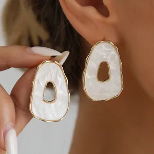 Detailed close-up showing texture of vintage irregular white hollow earrings with gold rim
