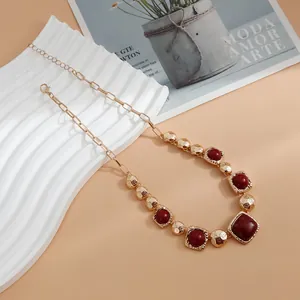 Close-up of vintage gold necklace with chunky links and red geometric stones.