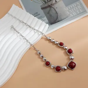 Macro view of a vintage silver chain necklace featuring bold red geometric square beads