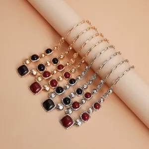 Close-up detail of vintage geometric square necklaces with red and black stones in gold tones