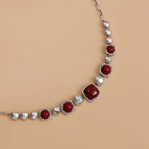 Detail of vintage geometric necklace with red square stones and textured silver metal
