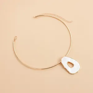 Detail view of retro gold choker with irregular hollow white shell pendant.