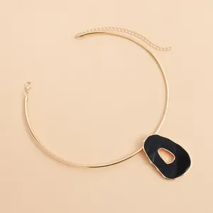 Close-up of a retro gold neck ring with an irregular black hollow pendant.