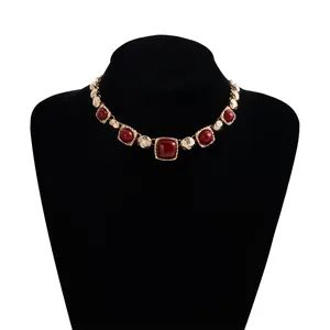Macro detail of a vintage gold geometric necklace with deep red square and round stones