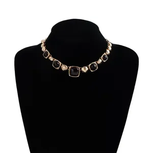 Detailed display of vintage gold-tone necklace with black geometric stones on black velvet bust