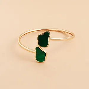 Detailed view of a vintage style gold bangle featuring two irregular green resin stones