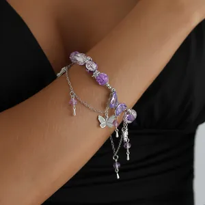 Vue détaillée d'un bracelet à pampilles papillon violet porté élégamment au poignet