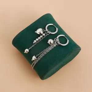 Detailed macro view of silver hoop earrings with long chain tassels and heart charms