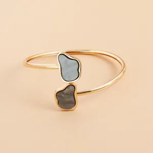 Detail view of gold-tone open bangle with irregular grey stone accents
