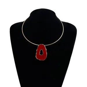 Detail view of a retro irregular red hollow pendant on a gold-tone choker necklace