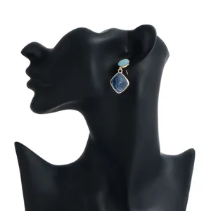 Elegant detail of geometric blue enamel drop earrings displayed on a black mannequin bust