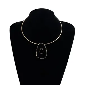 Close-up of a retro irregular hollow black pendant on a sleek thin gold choker