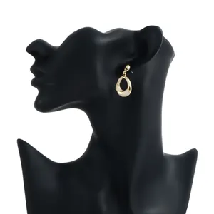 Close-up detail of elegant gold-toned geometric earring featuring a cream enamel inlay