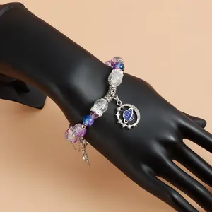 Détail d'un élégant bracelet violet avec breloque planète et glands sur mannequin