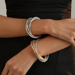 Detailed close-up showing multi-layer metallic snake bone bracelets on a female model wrist