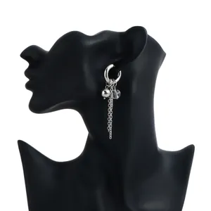 Macro detail showing a stylish silver dangling earring with hoop bead and long chain tassel.