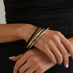 Close-up of three stacked bangles in dark brown, gold, and silver metallic finishes.