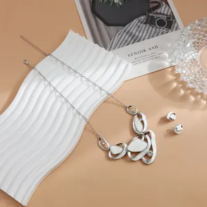 Close-up of French style silver-tone necklace and earring set with white pleated shapes
