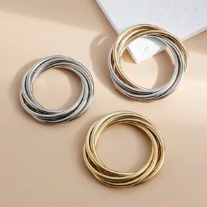 Detailed macro view of layered snake bone chain bracelets in gold and silver metallic finish