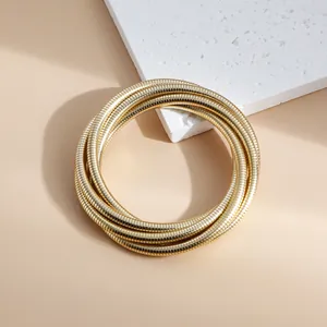 Close-up view of a vintage gold multi-layered snake chain stacking bracelet on stone.