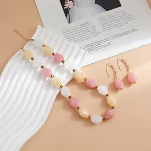 Detailed view of retro acrylic beaded necklace and earrings in pink and cream