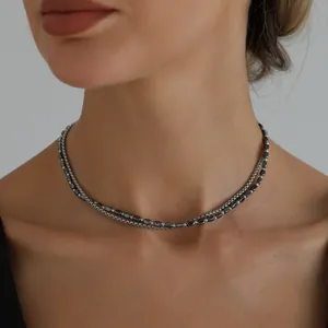 Dettaglio ravvicinato di una collana a due strati di perle di ematite su una modella.