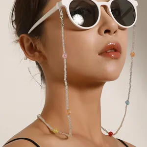 Dettaglio di una donna che indossa un'elegante catenella per occhiali con perline colorate.