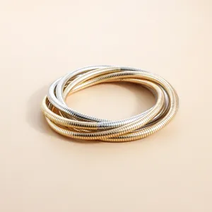 Close-up of retro layered metallic snake-bone stretch bracelets in gold and silver.