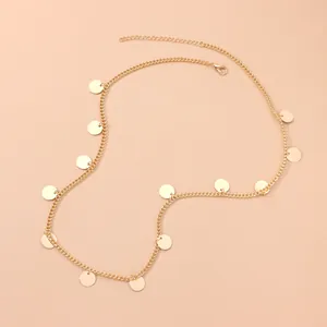 Detail showing a minimalist gold metal chain headband with round sequin tassels