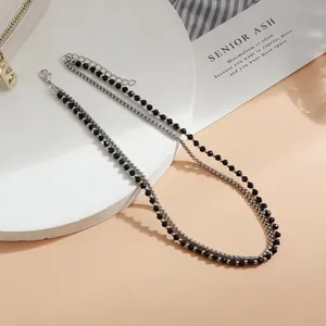 Vista dettagliata di una collana a due strati con perle nere e catena d'argento.