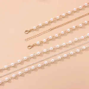 Detailed macro view of handmade faux pearl and metal link chains for hair accessories.