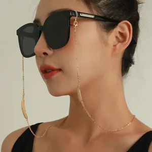 Gros plan d'une chaîne de lunettes en alliage doré avec motif plume sur un mannequin.