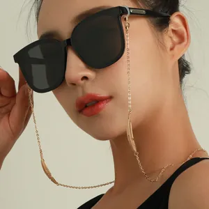 Gros plan d'une chaîne de lunettes en plumes dorées sur un mannequin avec lunettes