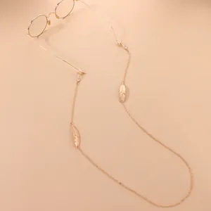 Vue détaillée d'une chaîne de lunettes dorée ornée de breloques plumes élégantes.