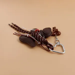 Detailed view of brown braided ribbon keychain with silver carabiner and heart charms.
