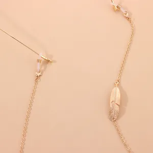 Vue détaillée d'une chaîne de lunettes minimaliste dorée avec pendentif plume en métal.