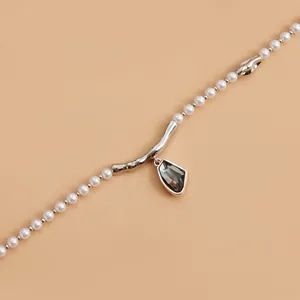 Elegante collar de perlas con detalle de rama plateada y colgante de cristal gris humo.