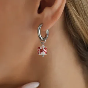 Detailed view of silver hoop earring with red floral print square ceramic bead