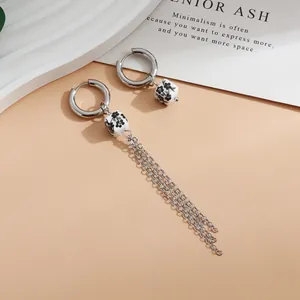 Close-up of asymmetric silver hoop earrings with floral ceramic beads and chain tassels