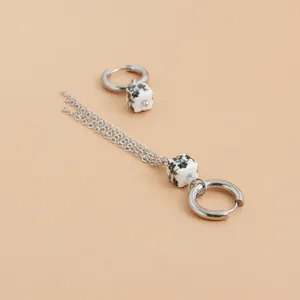 Close-up detail of silver hoop earrings with floral ceramic cubes and chain tassel