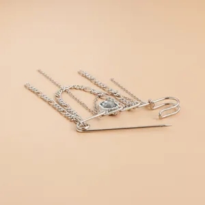 Detailweergave van een zilveren broche met meerdere kettingen en een glazen steen.