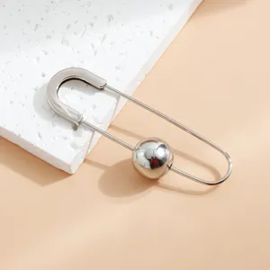 Détail d'une broche épingle de sûreté argentée avec une perle métallique lisse.