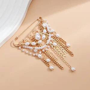 Detail view of a vintage pearl tassel brooch with multi-layer gold chains and wheat charms