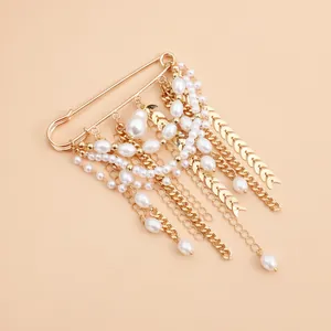Detail view of a vintage pearl multi-chain brooch with golden wheat ear charms on beige background.